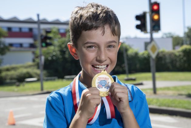 Kind mit goldener Medaille vor Ampel
