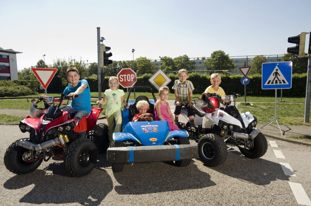 Kinder in Kinderfahrzeugen vor Verkehrszeichen
