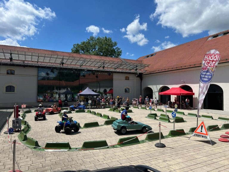 Übersicht über den Kiddi-Car Parcours beim KNAX-Fest 2025 im Kloster Fürstenfeld in Fürstenfeldbruck. Kinder fahren mit Elektroautos und Quads bei sommerlichen Temperaturen durch den Innenhof.